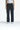 Eine Person, die ein weißes ärmelloses Top, 2Y Studios Anela Worker Baggy Jeans in verwaschenem Schwarz von 2Y Women und weiße Sneakers trägt, steht vor einem schlichten weißen Hintergrund.