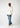 Eine Person mit geflochtenen Haaren steht in entspannter Pose und trägt einen beigen Kapuzenpullover von Eightyfive, dazu ein weißes T-Shirt, hellsandblaue Open Hem Jeans von Eightyfive und beige Sneakers vor einem schlichten Hintergrund.