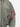 Eine Nahaufnahme des grünen Alpha Industrie Ma-1 Heritage Vintage Green Ärmels mit einer Reißverschlusstasche und dem charakteristischen roten "Remove Before Flight"-Tag - ein ikonisches Alpha Industrie Teil im klassischen Militärstil.