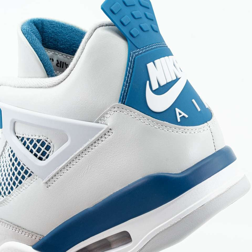 Nahaufnahme eines weißen und in Military Blue gehaltenen Nike Air Jordan 4 Retro Sneakers mit Logo, Mesh-Details und Fersendämpfung.