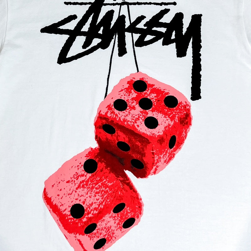 Stüssy Fuzzy Dice T-Shirt mit einer Grafik aus zwei hängenden roten Würfeln und schwarzem stilisiertem Text darüber, online verfügbar.