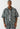 Ein Mann steht mit dem Gesicht nach vorne und trägt ein True Religion Super T Oversize Jacquard Shirt Dark Wash mit passender Hose in grauem und schwarzem Camouflage-Muster.