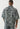 Ein Mann steht mit dem Rücken zur Kamera und trägt ein True Religion Super T Oversize Jacquard Shirt in Dark Wash und eine passende Hose, beide mit weißen Nähten.